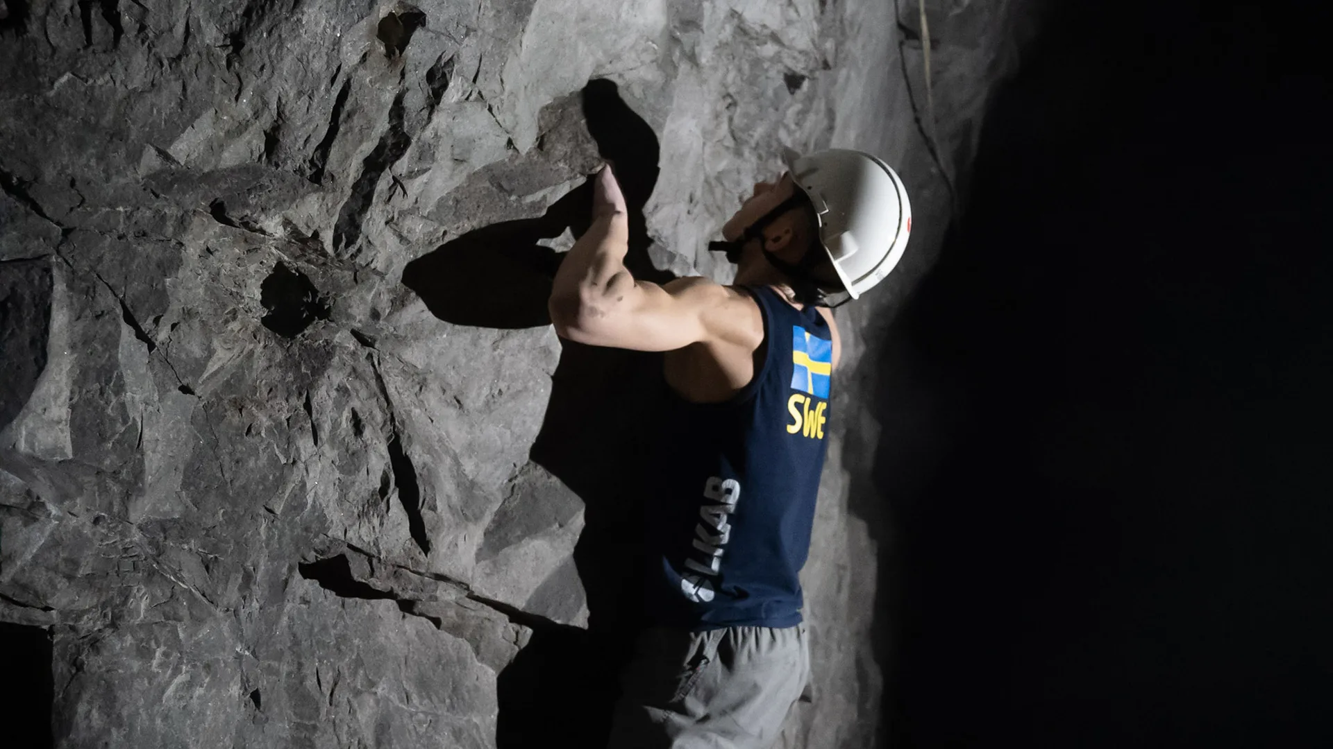 Man in helmet climbing a rock wall.