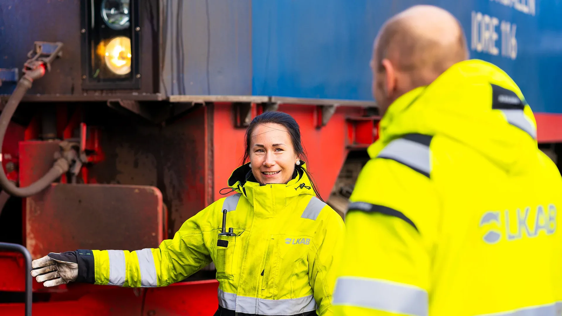 Två personer i varselkläder står vid tåg.