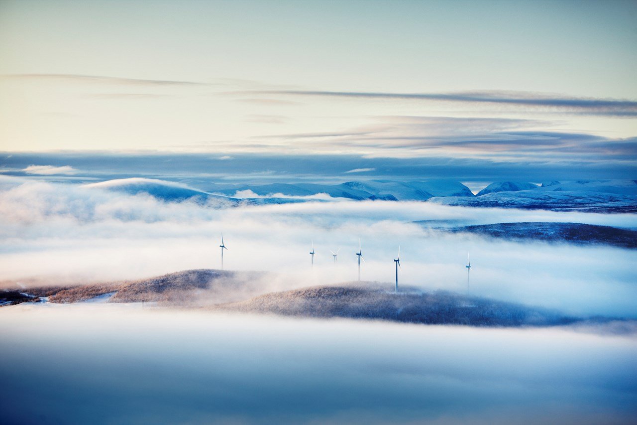 Vybild över vindkraftverk i dimma