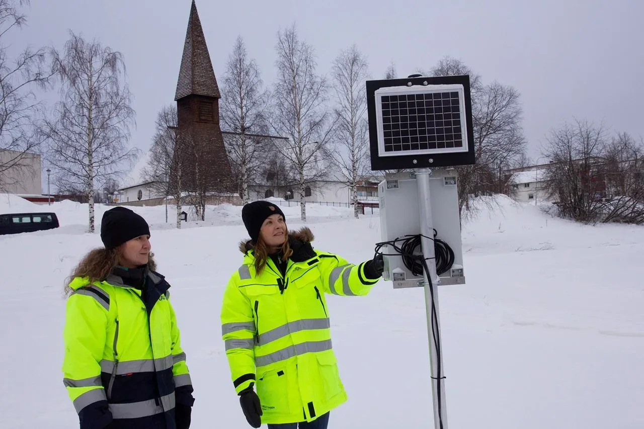 Två kvinnor i varseljackor kontrollerar mätstation.