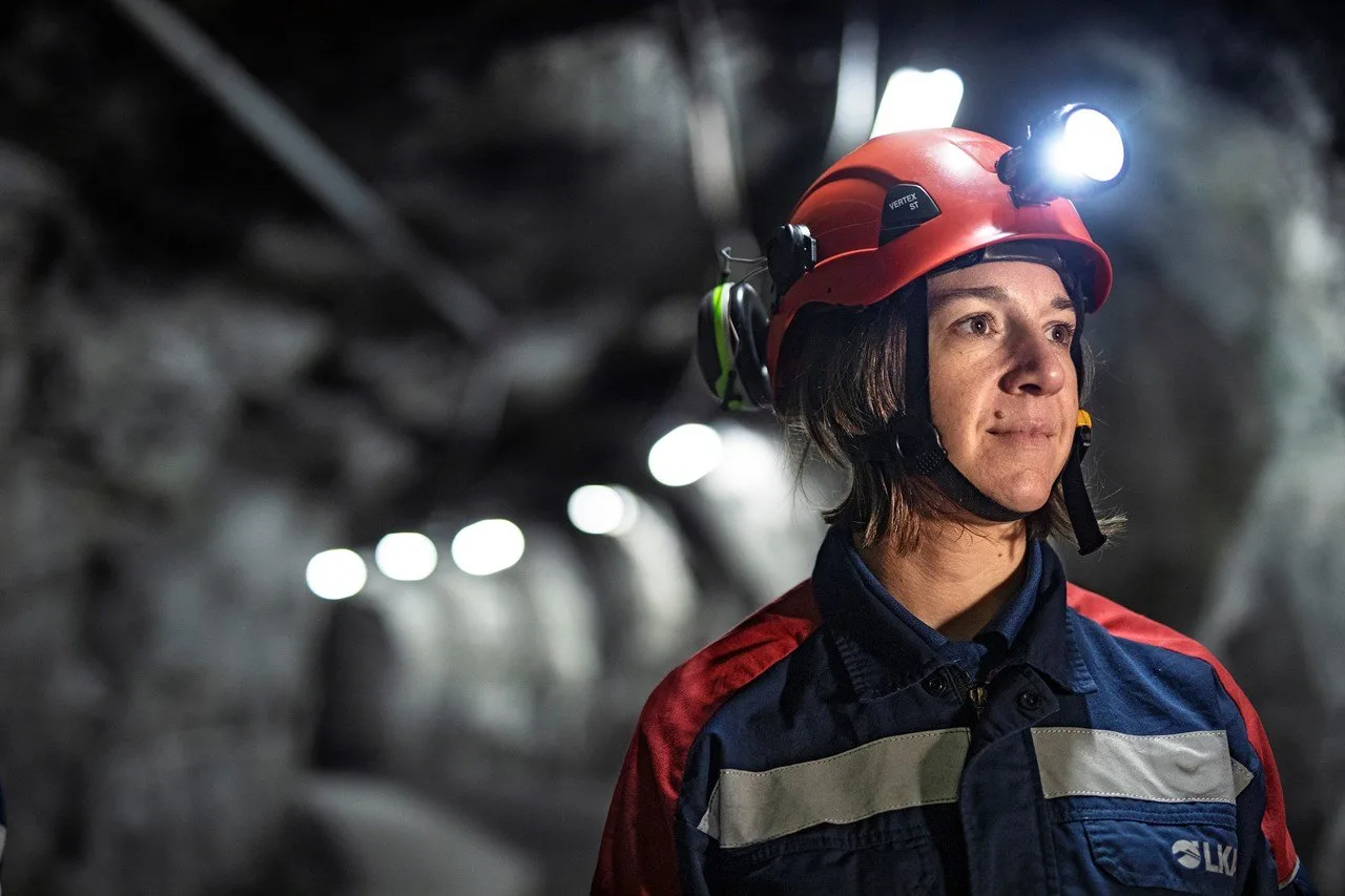 Woman in work clothes and mining helmet under ground