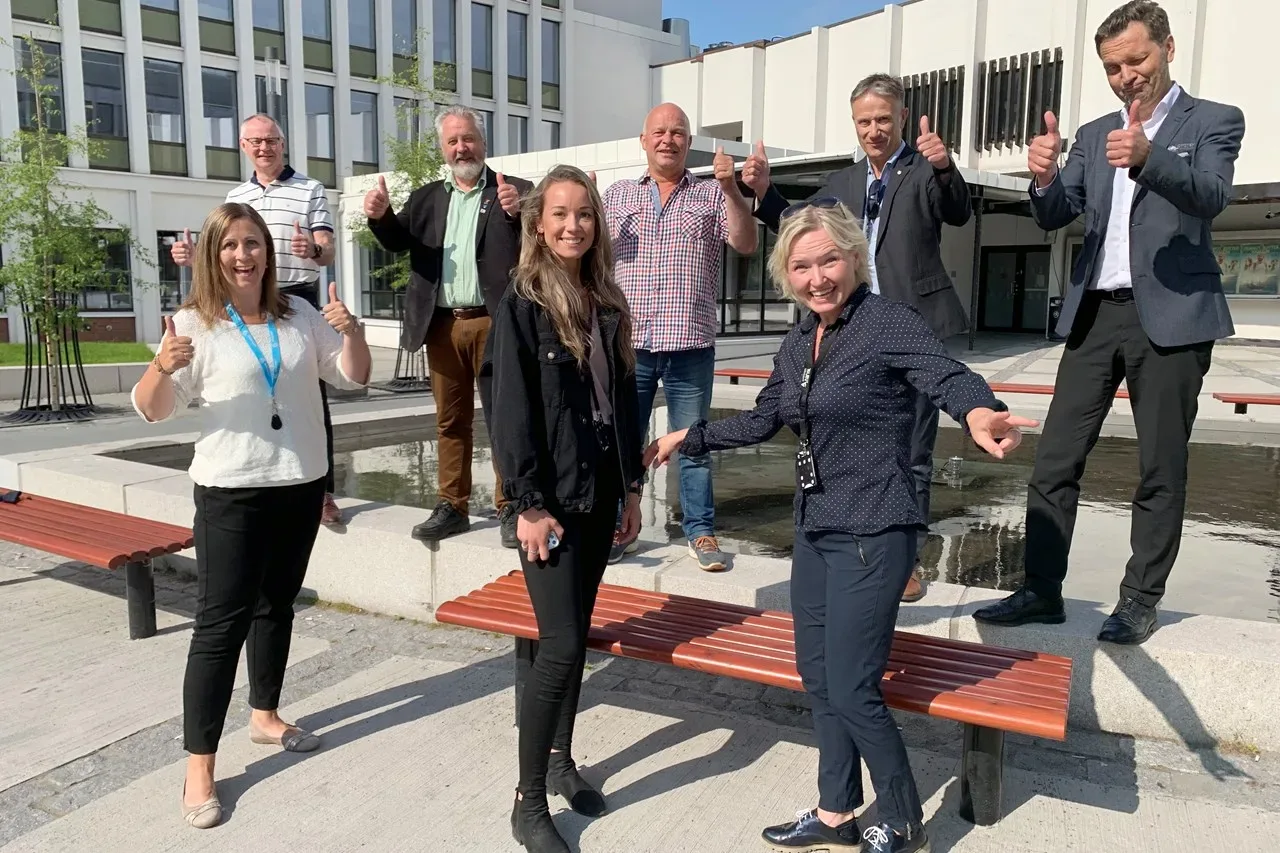 Åtta glada personer gör tummen upp på torget i Narvik