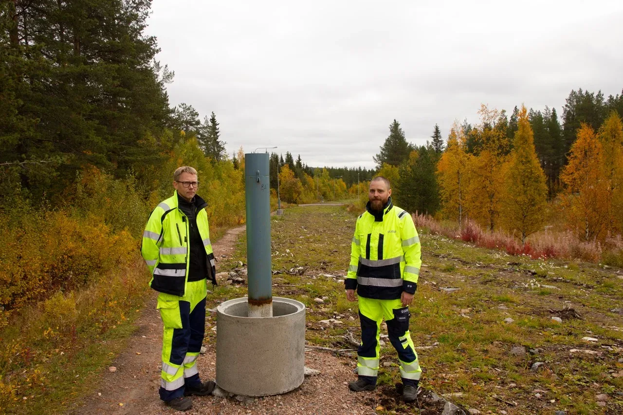 Två personer stående vid ett betongfundament. 