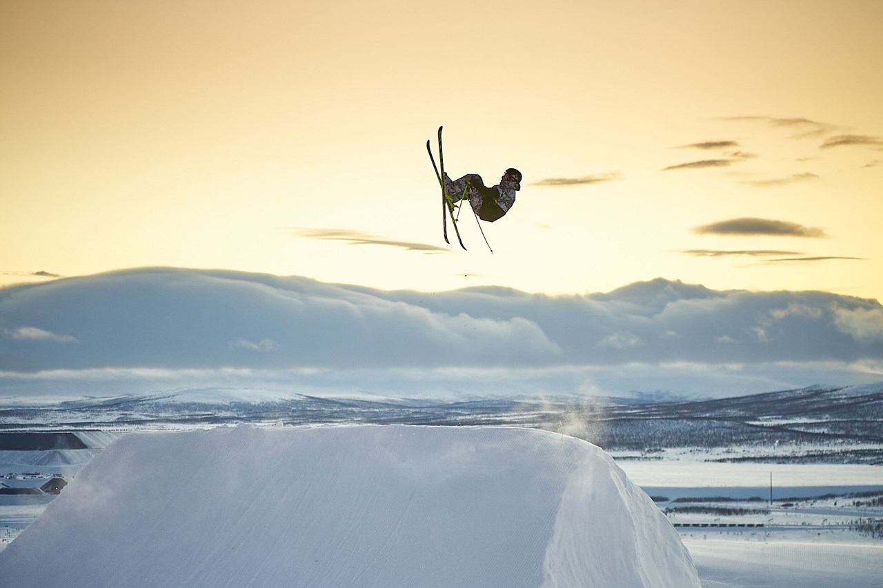 Snowboardåkare hoppar mot solnedgång