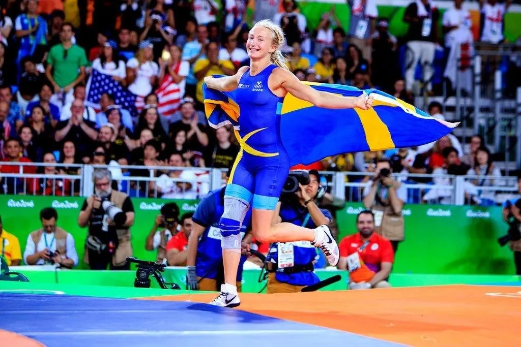 Sofia Mattsson springer över brottarmattan med svensk flagga