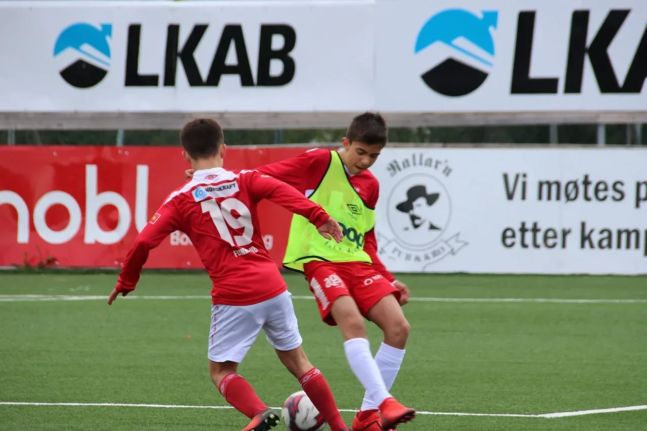 Två unga fotbollsspelare framför LKAB-skyltar