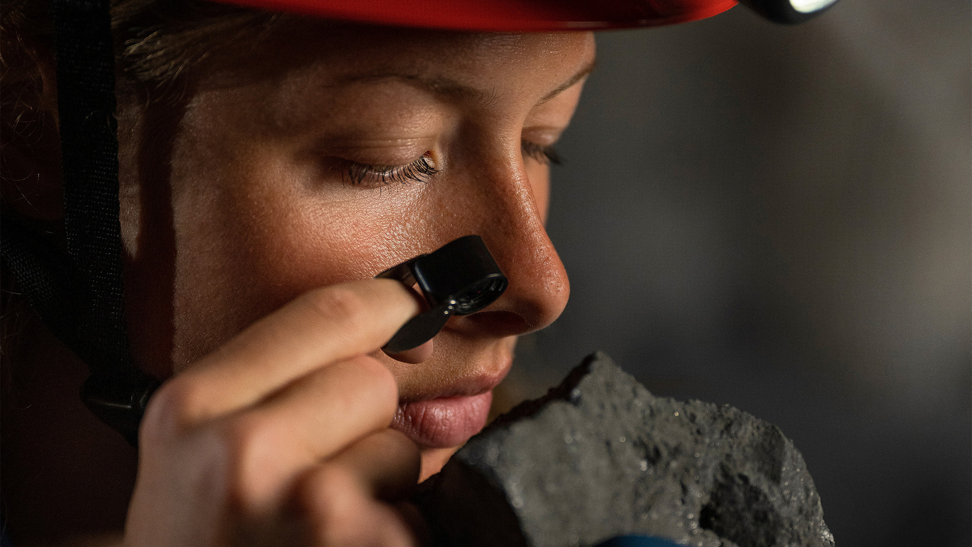Woman studying a piece of iron ore. 
