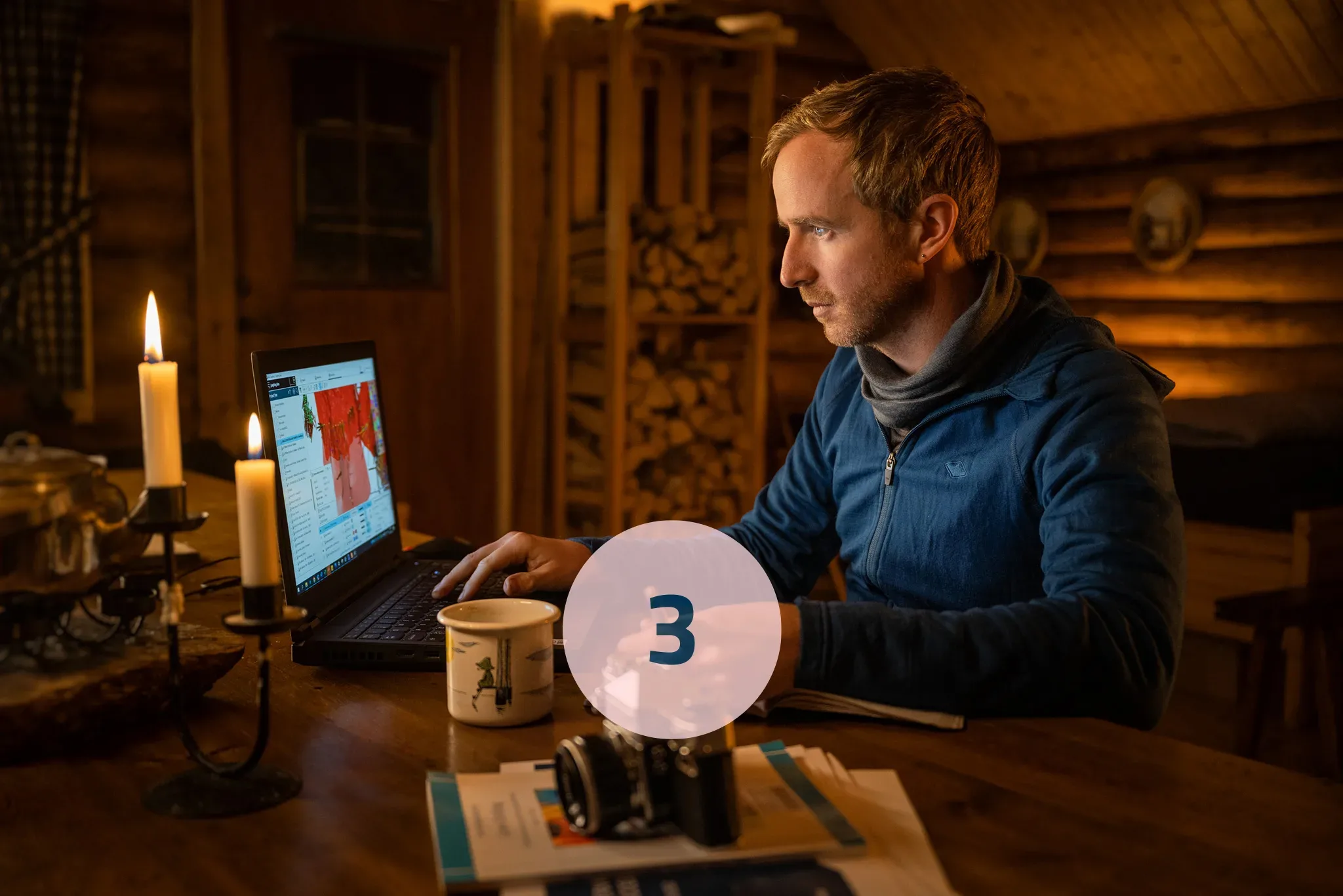 Man sitting at computer in cozy cabin environment. 