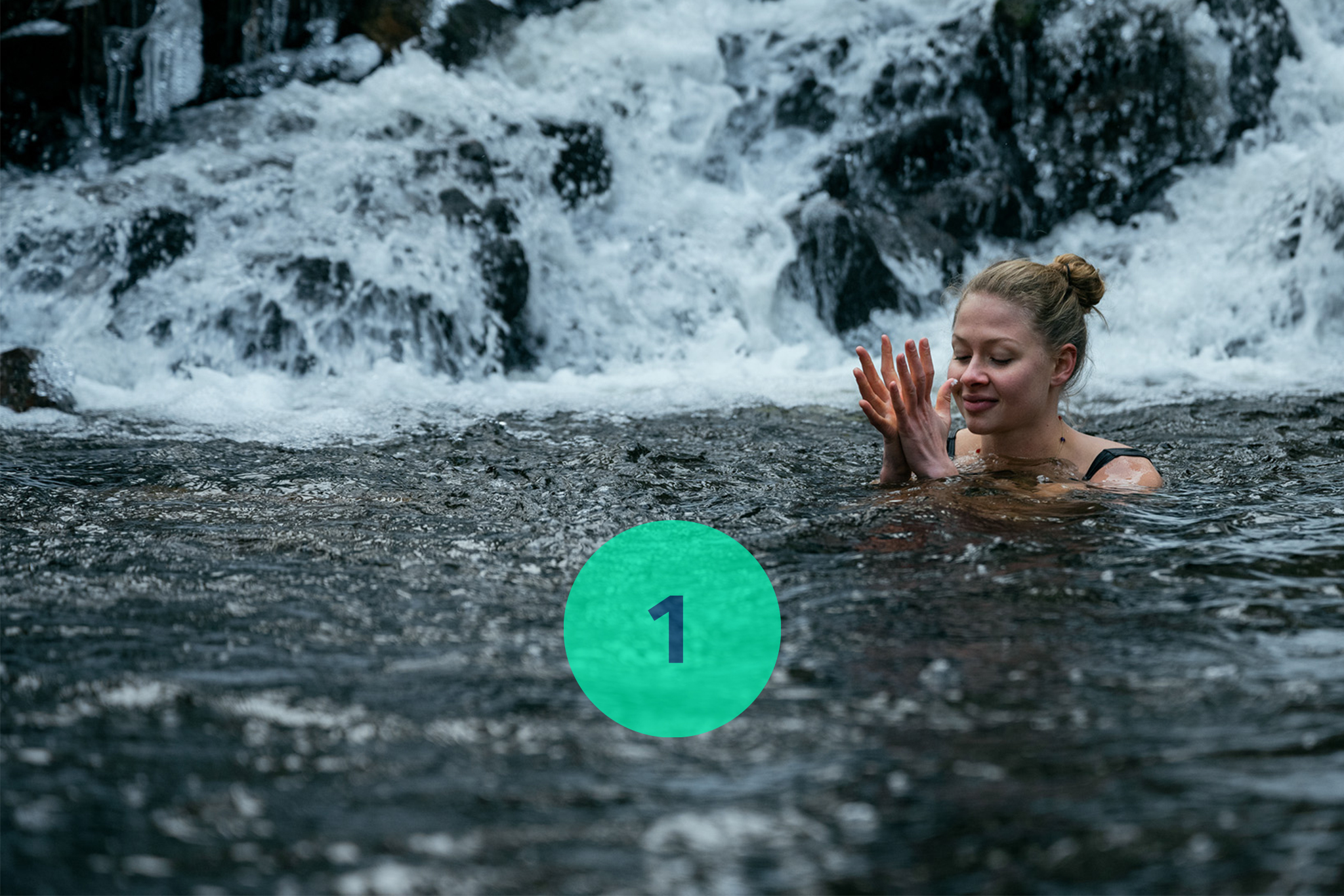 Woman swimming beneath waterfall. 