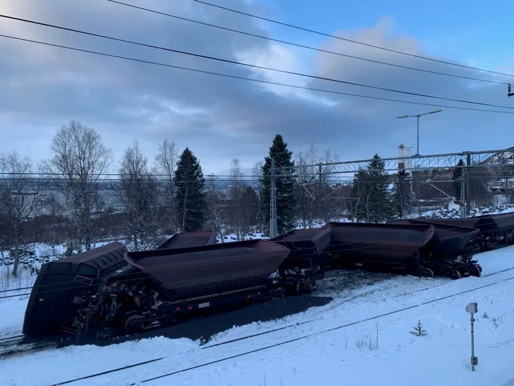 Urspårade vagnar. På och bredvid spåret ligger högar av järnmalmspellets.