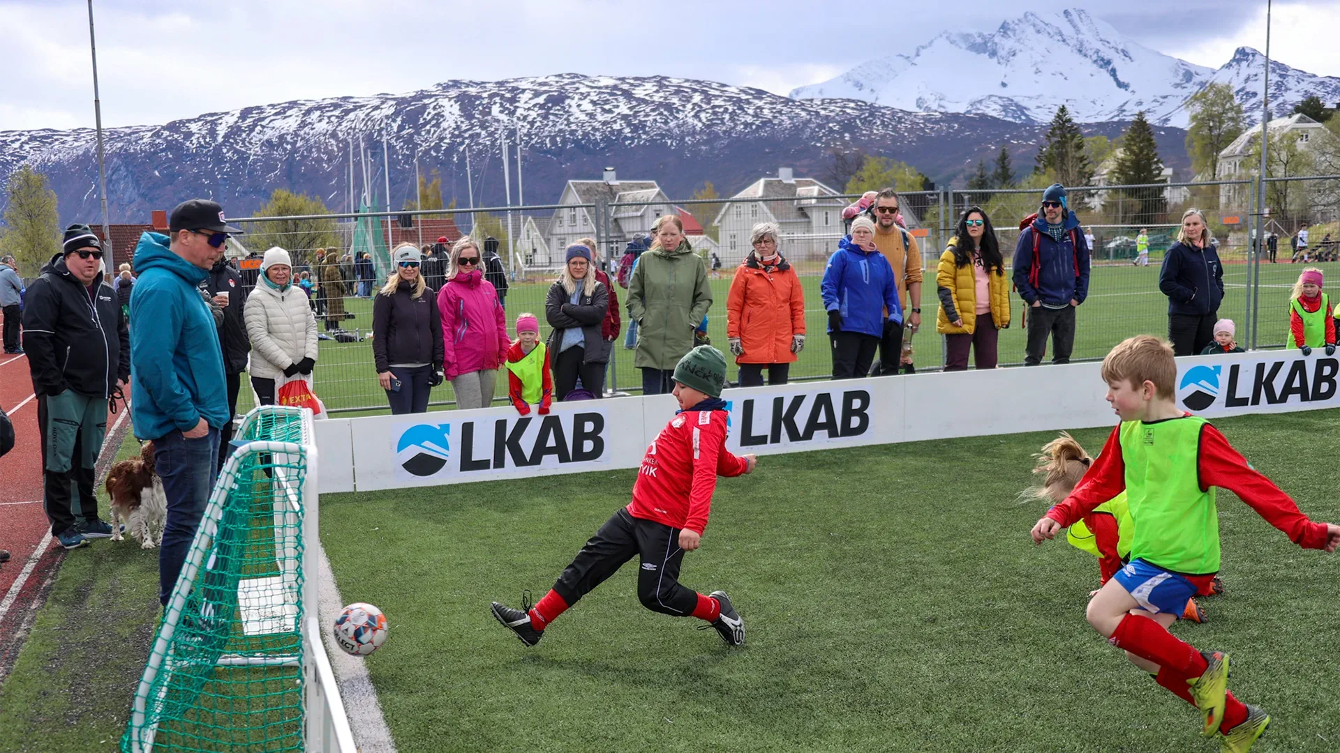 Två unga pojkar spelar fotboll inför publik.