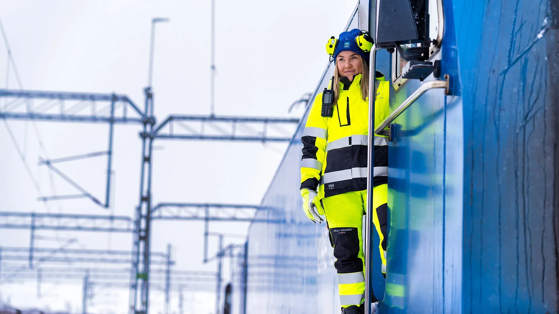 Kvinna i varselkläder vintertid, ståendes på ett tåglok.