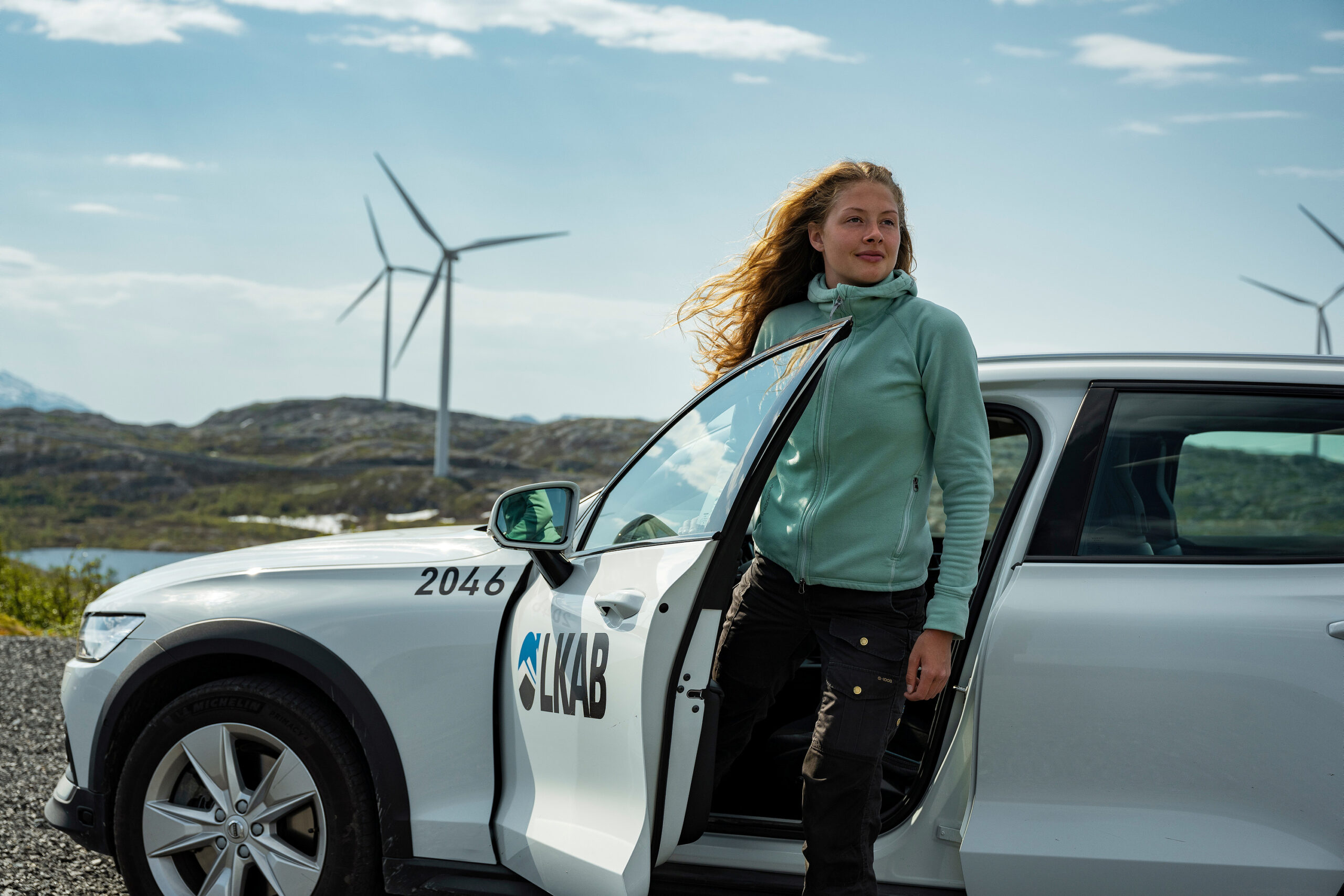 Woman getting out of car, with wind turbines in background