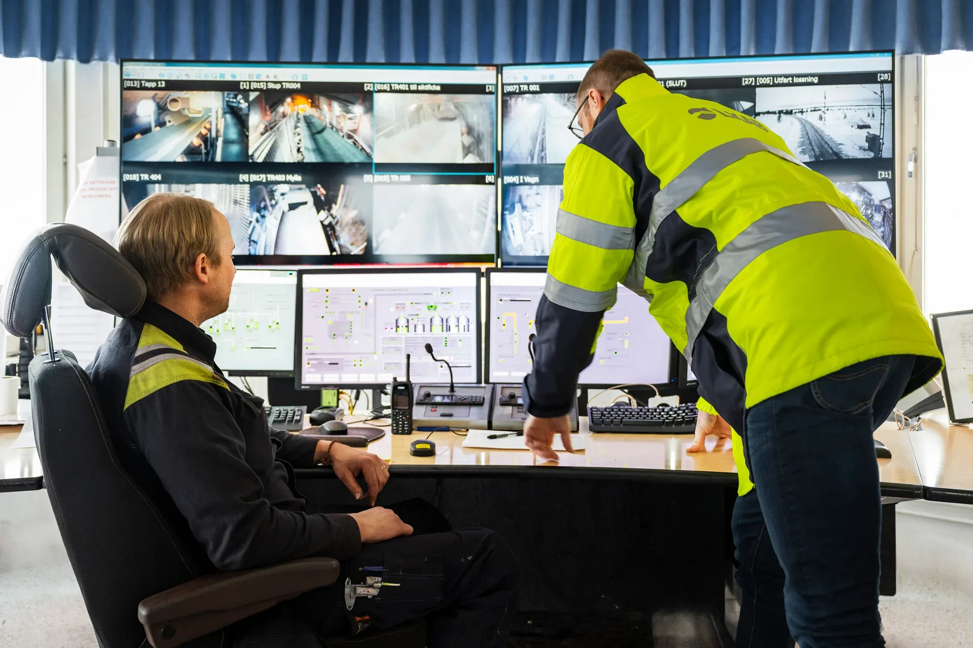 Two people in work clothes in a control room