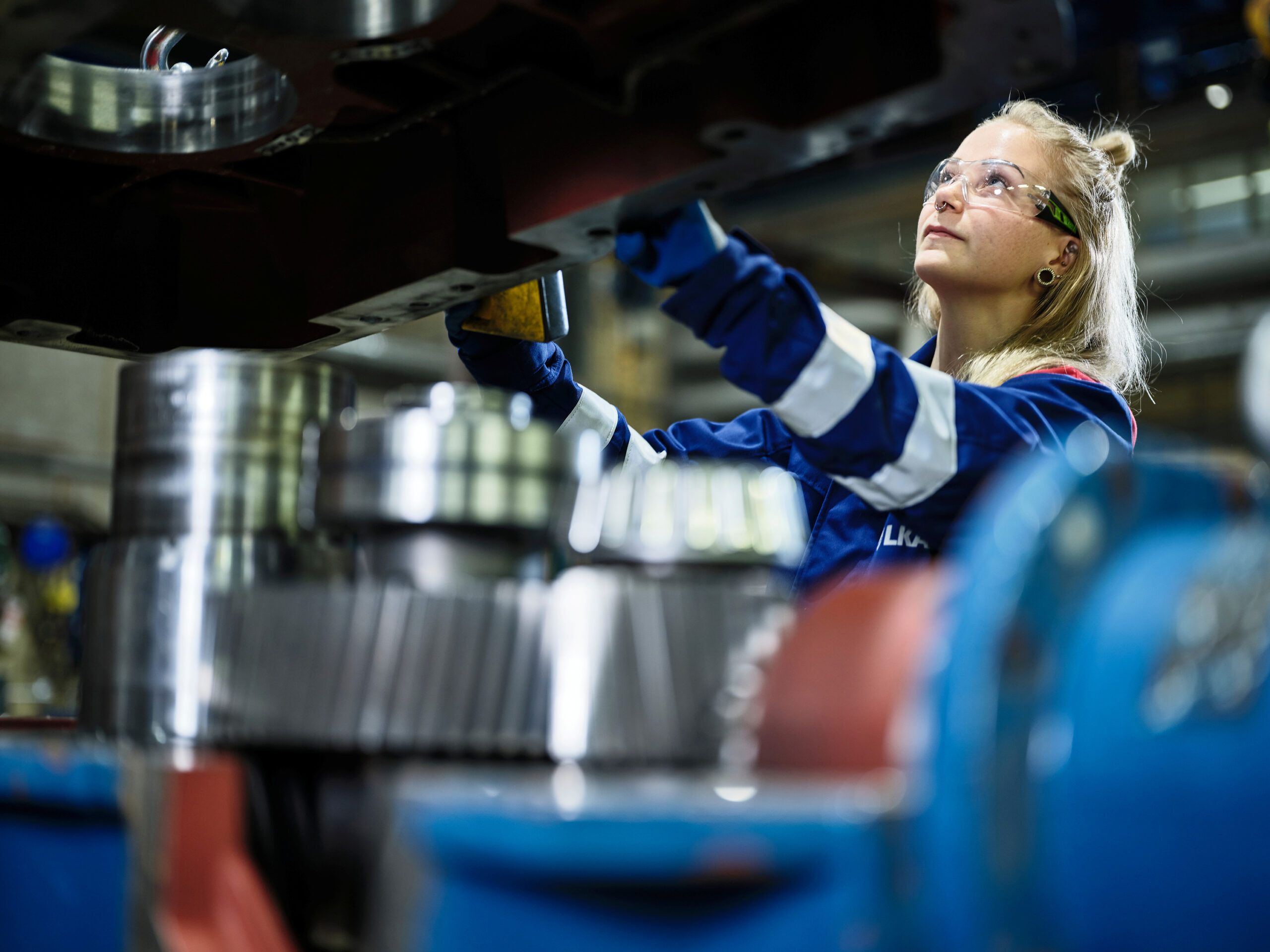 Woman in protective googles working on a gear box