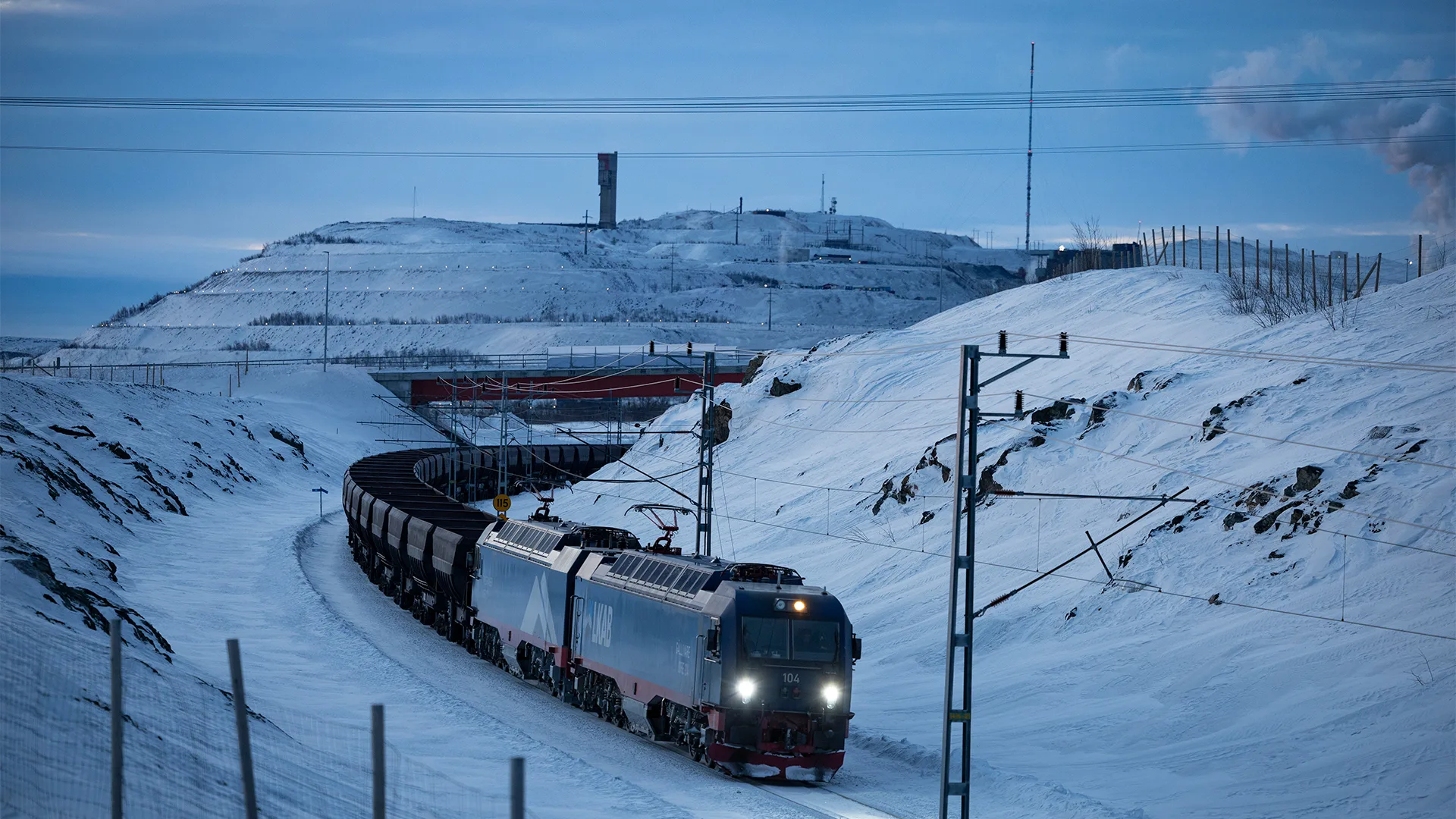 Malmtåg i vintermiljö med gruvan i Kiruna i bakgrunden