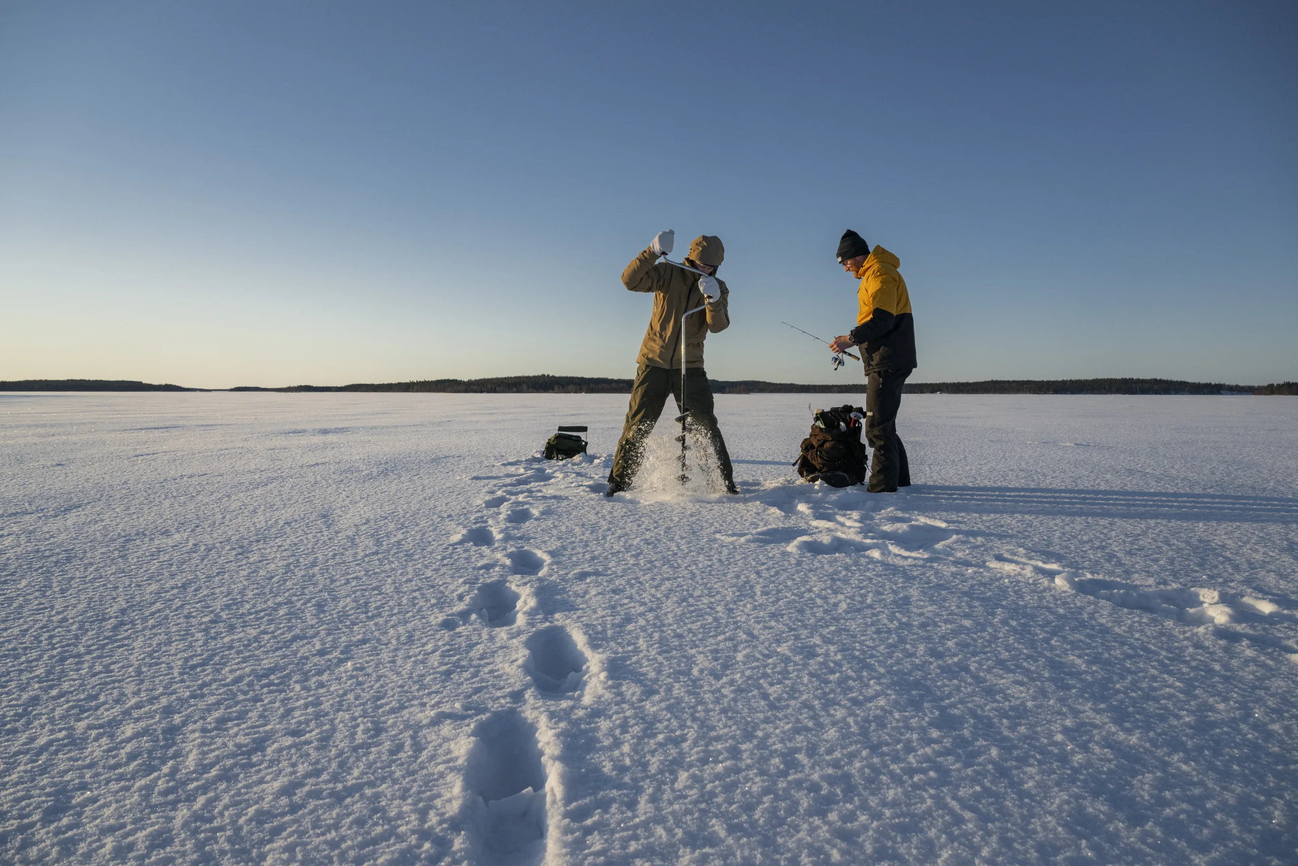 Två personer utomhus med isborr.