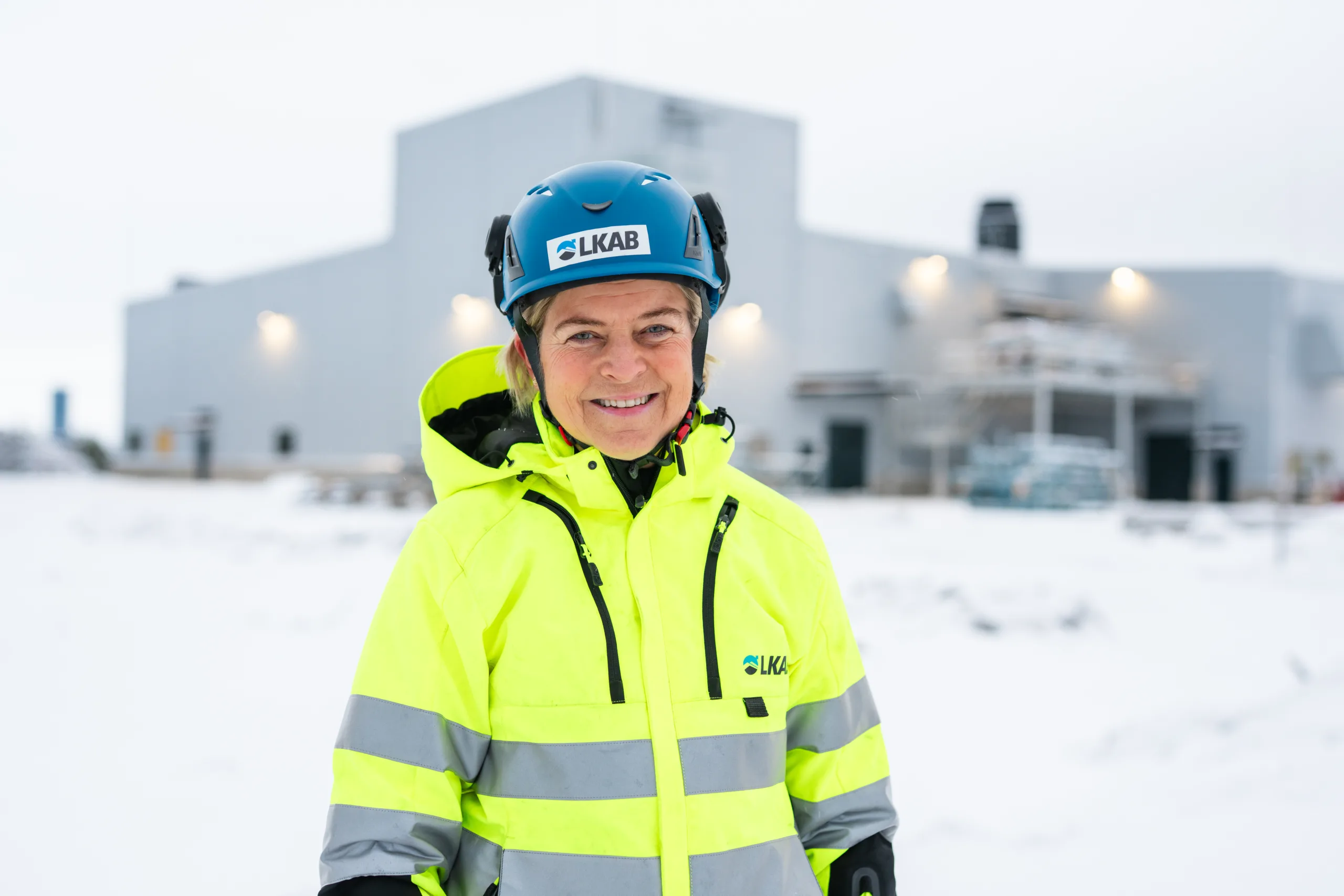 Porträttbild av kvinna i varselkläder och hjälm.